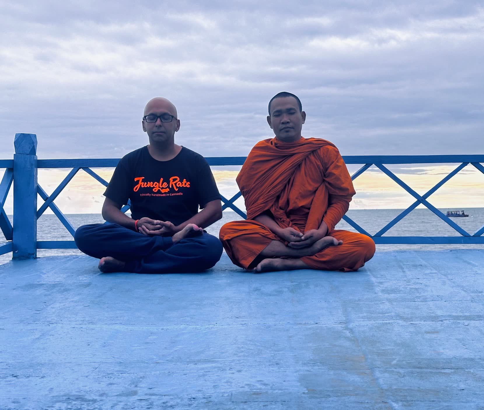 David Chung meditating with a monk by the sea in Cambodia
