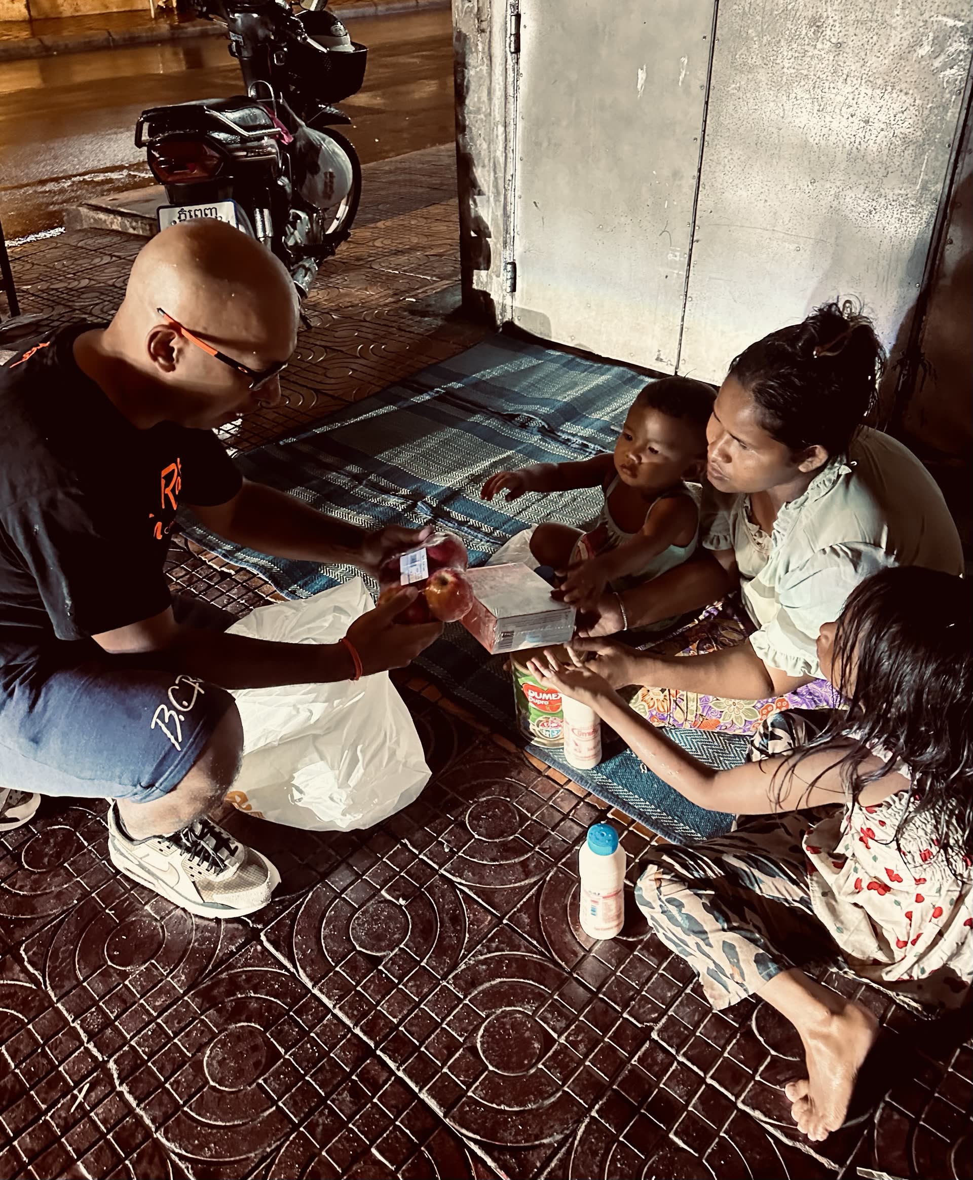 David Chung handing relief goods to a family in the street in Cambodia